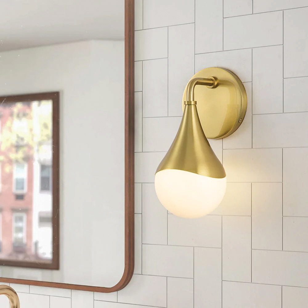 Wall-mounted sconces beside a mirror provide flattering light for grooming, while overhead lighting brightens the room